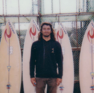 Surfer (Miguel Blanco) standing in front of his Polyola Surfboard Quiver