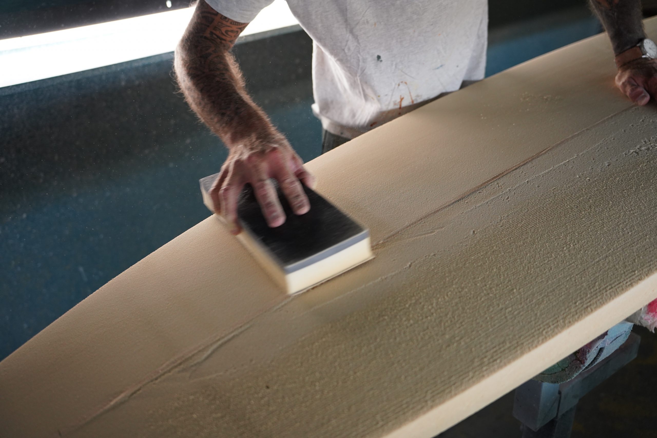 Shaper using a sanding block to refine the remaining unevenness. 
