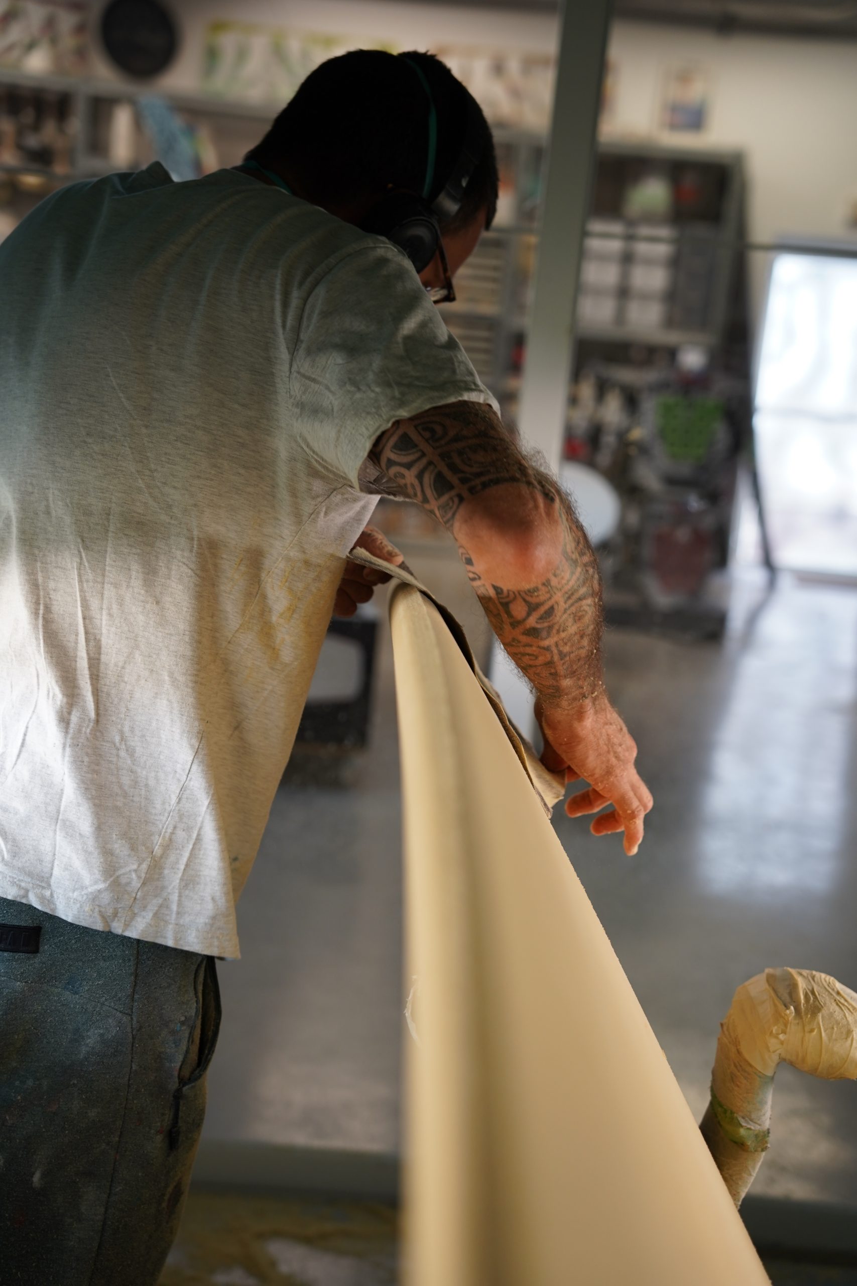 Shaper using sandpaper working on the rail of the surfboard