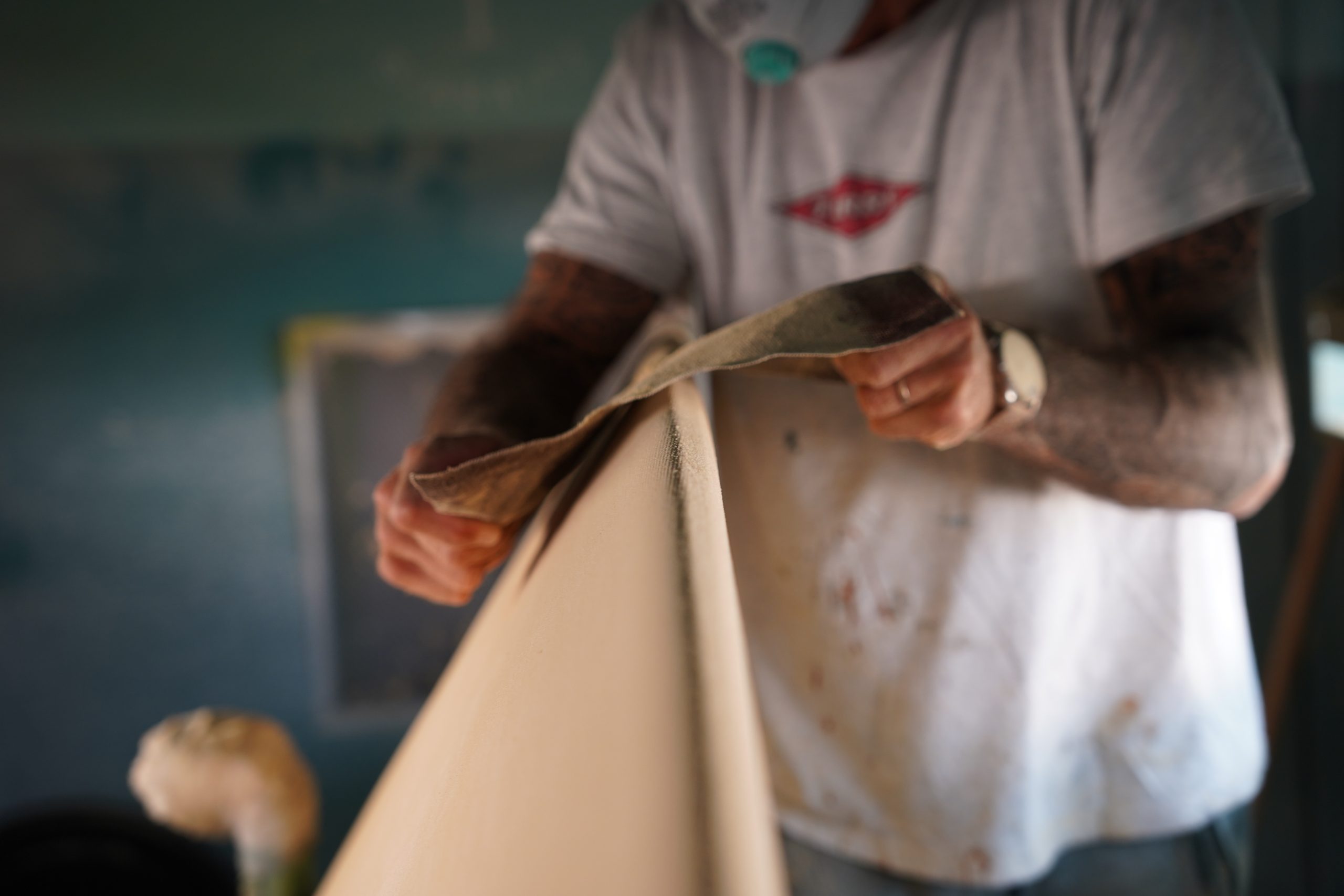 Shaper using sandpaper to finish the rail of the surfboard